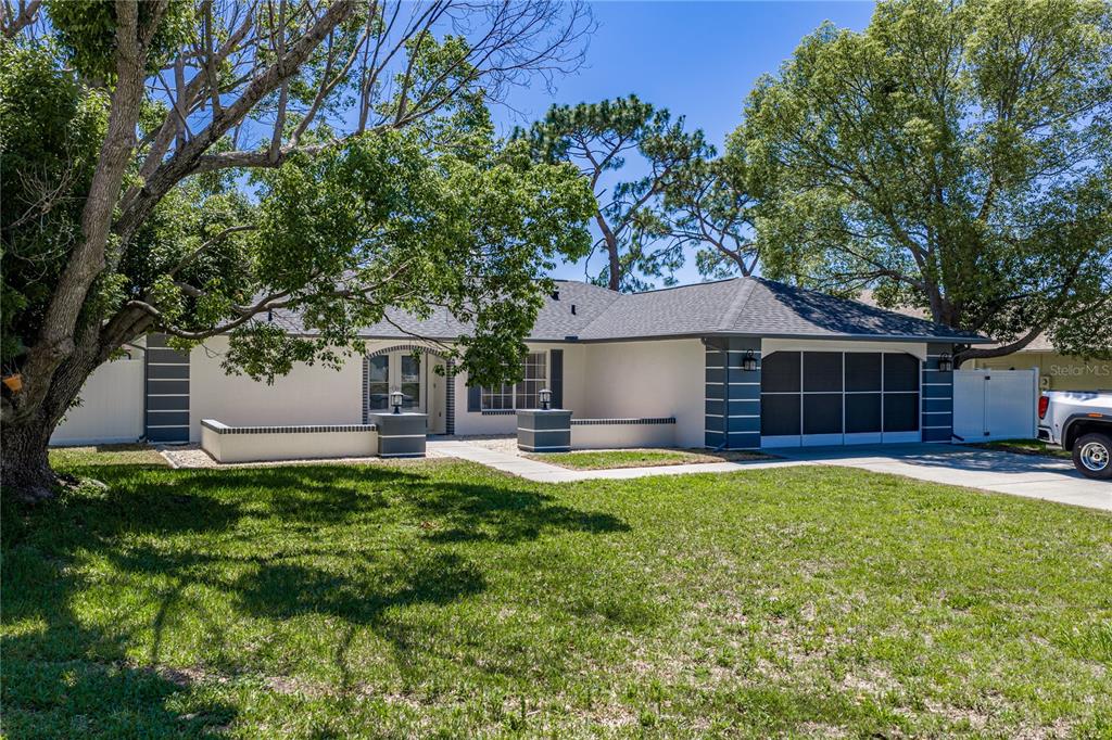 A single-story house with a white exterior, dark gray trim, and a screened-in garage — 7435 KILBRIDE COURT, WEEKI WACHEE, FL