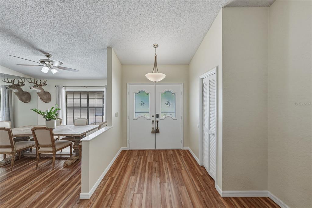 An entryway with wood-look flooring, a double front door, and a view into the dining room — 7435 KILBRIDE COURT, WEEKI WACHEE, FL