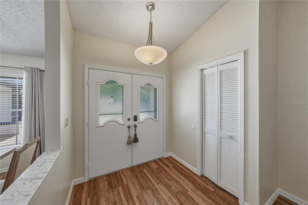 An entryway features double doors with glass inserts, wood-look flooring, and a louvered closet door — 7435 KILBRIDE COURT, WEEKI WACHEE, FL