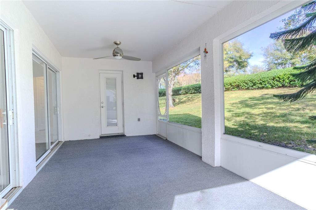 A screened-in patio with gray carpet, a ceiling fan, and sliding glass doors — 3667 KINGSWOOD COURT, CLERMONT, FL