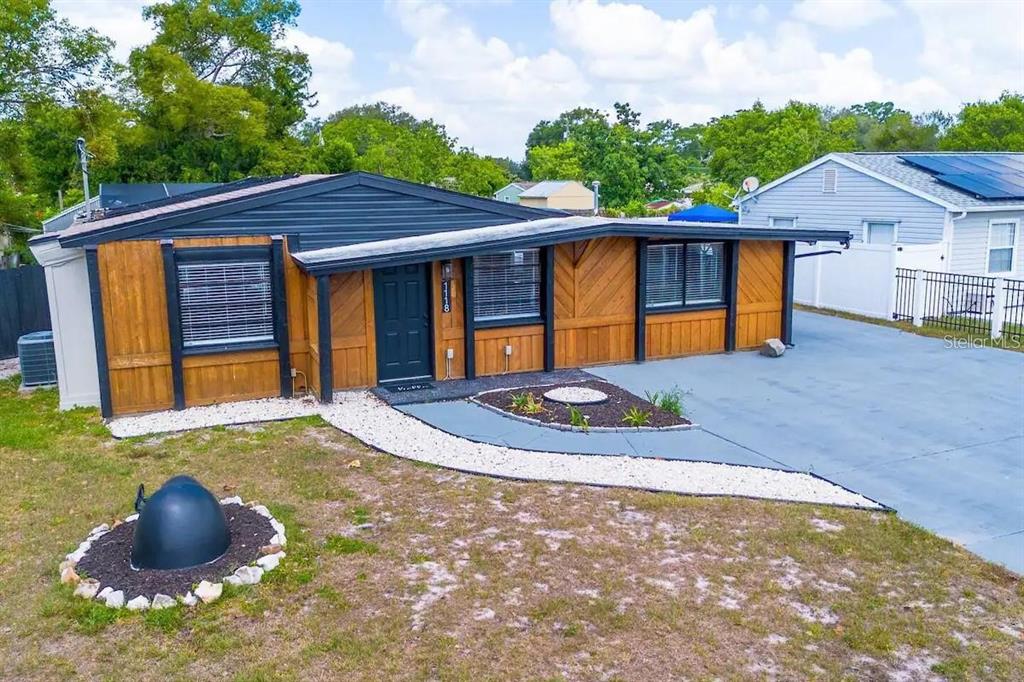 A single-story house with wood-paneled siding, a dark roof, and a white gravel walkway — 1118 OVERDALE STREET, ORLANDO, FL