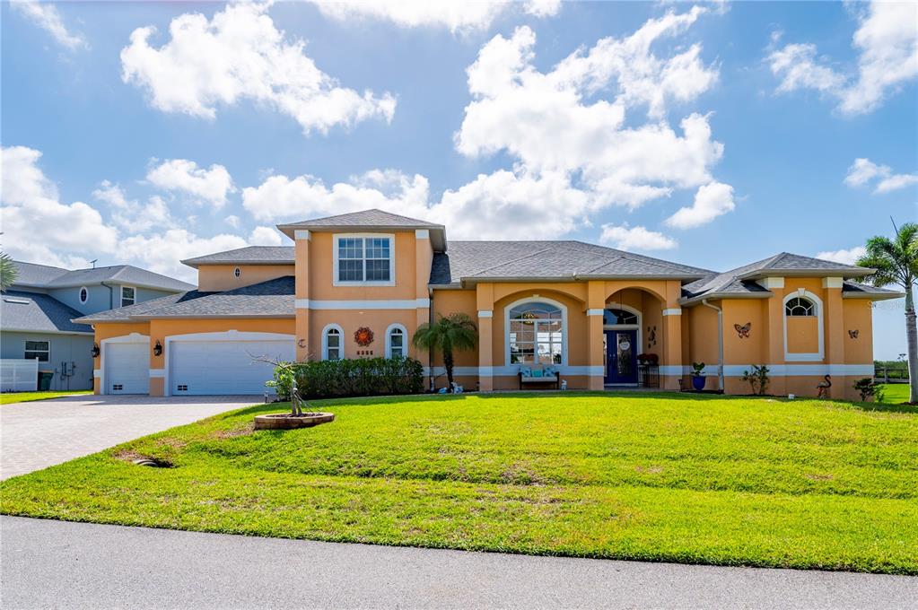 A single-story orange stucco house with a multi-car garage and a large front lawn — 1356 TREMONT TERRACE, PORT CHARLOTTE, FL