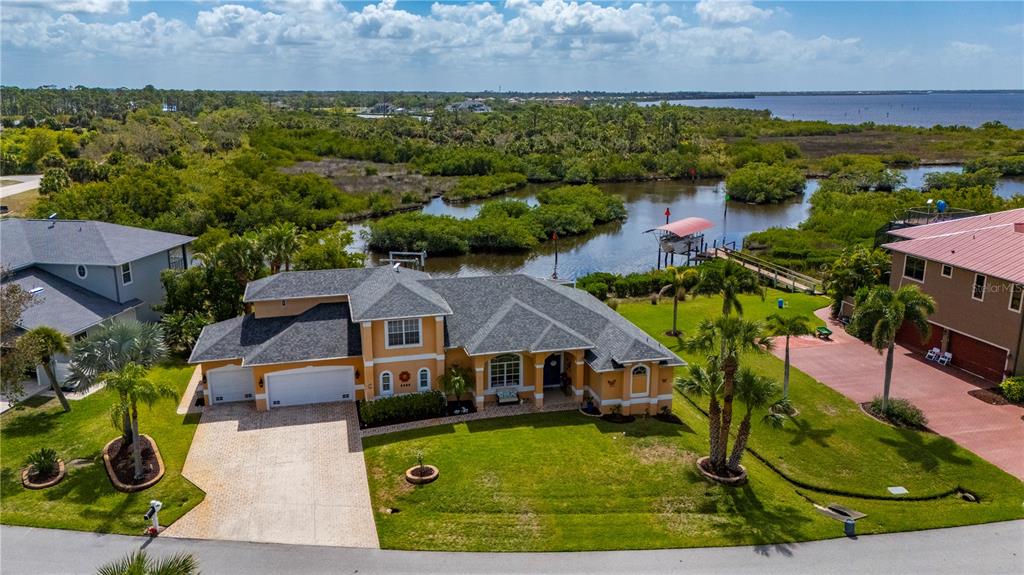 An aerial view of a tan house with a gray roof near a coastal waterway — 1356 TREMONT TERRACE, PORT CHARLOTTE, FL