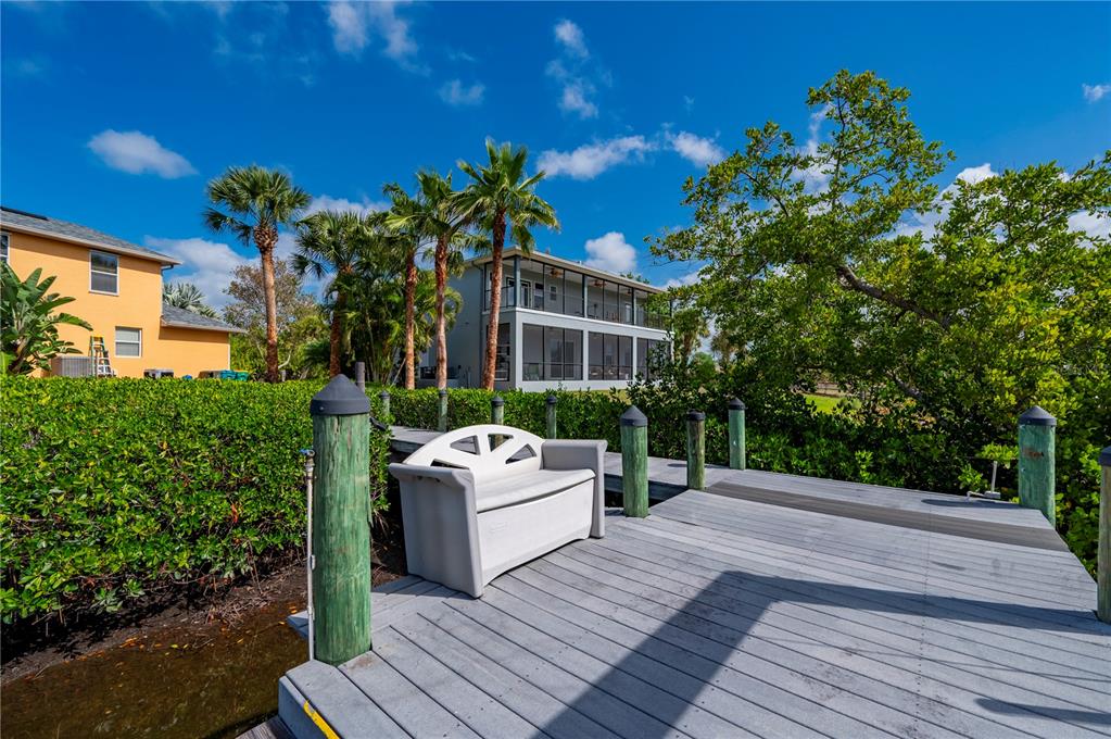 A wooden dock with a storage bench overlooks a canal and a multi-story house — 1356 TREMONT TERRACE, PORT CHARLOTTE, FL
