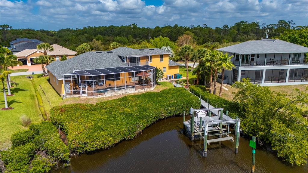 An aerial view shows a yellow house with a screened pool deck and a boat dock — 1356 TREMONT TERRACE, PORT CHARLOTTE, FL