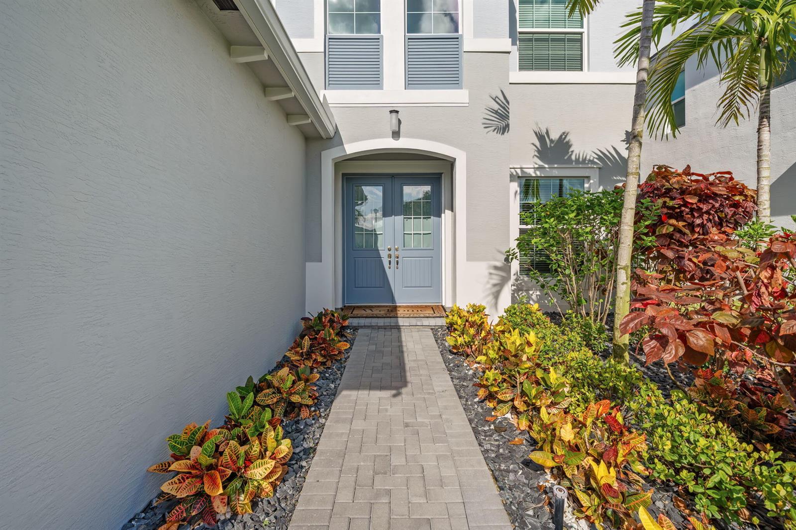 A paved walkway leads to the blue double front doors of a light-colored house — 5455 Empire Drive, Westlake FL 33470, WESTLAKE, FL