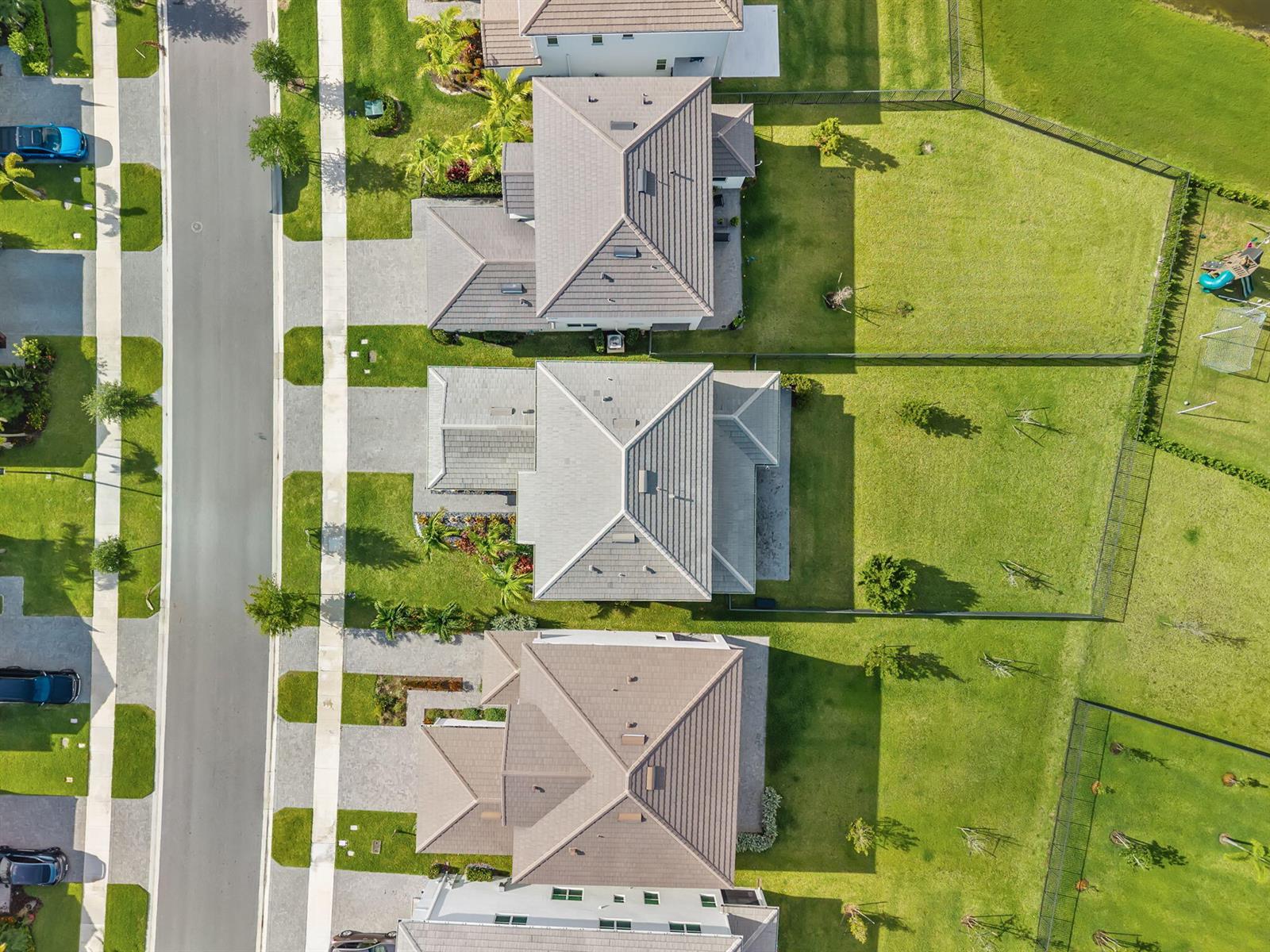 An aerial view shows three suburban houses with tiled roofs and large fenced backyards — 5455 Empire Drive, Westlake FL 33470, WESTLAKE, FL