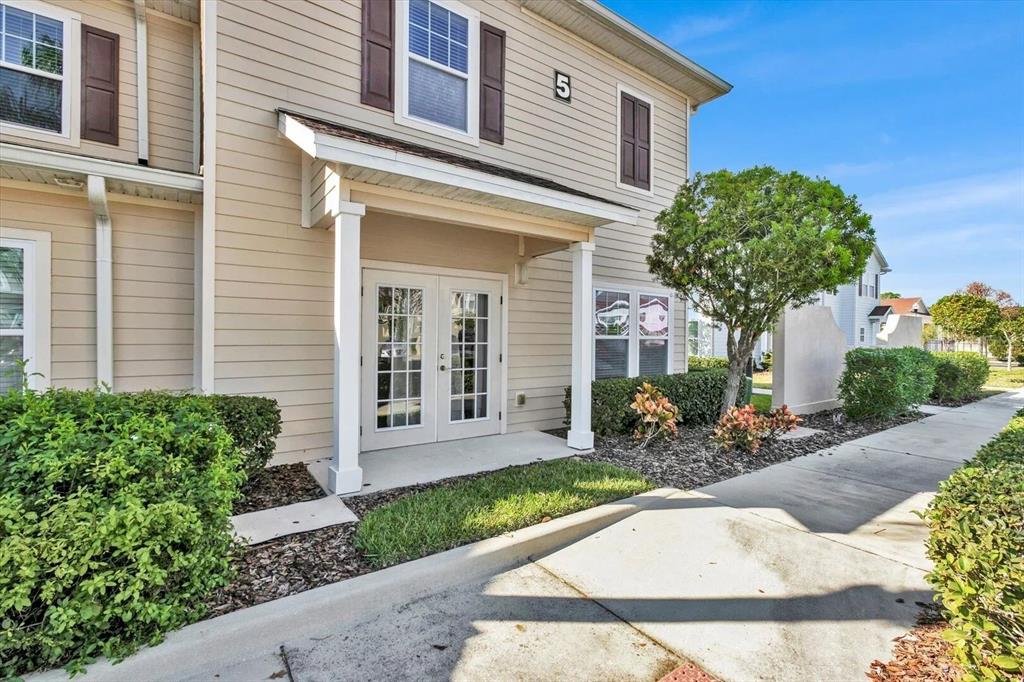 A two-story tan building with white trim, a covered entryway, and a concrete sidewalk — 3206 GOLD LANE, KISSIMMEE, FL