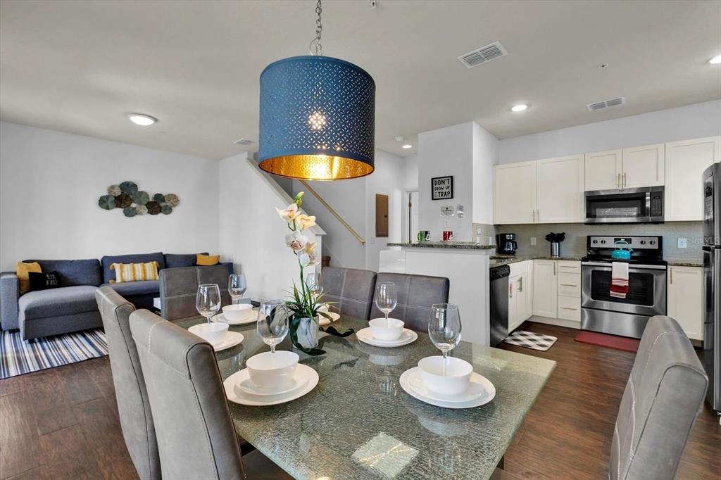 A dining area with a glass table and blue pendant light opens to a kitchen — 3206 GOLD LANE, KISSIMMEE, FL