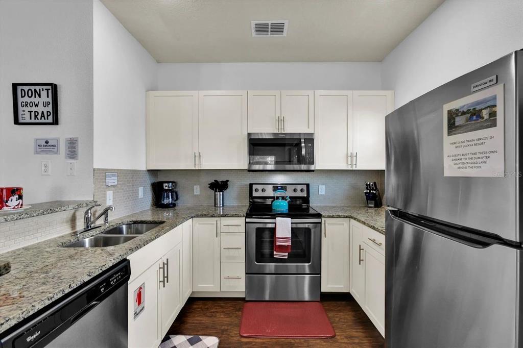 A kitchen features white cabinets, stainless steel appliances, and granite countertops — 3206 GOLD LANE, KISSIMMEE, FL