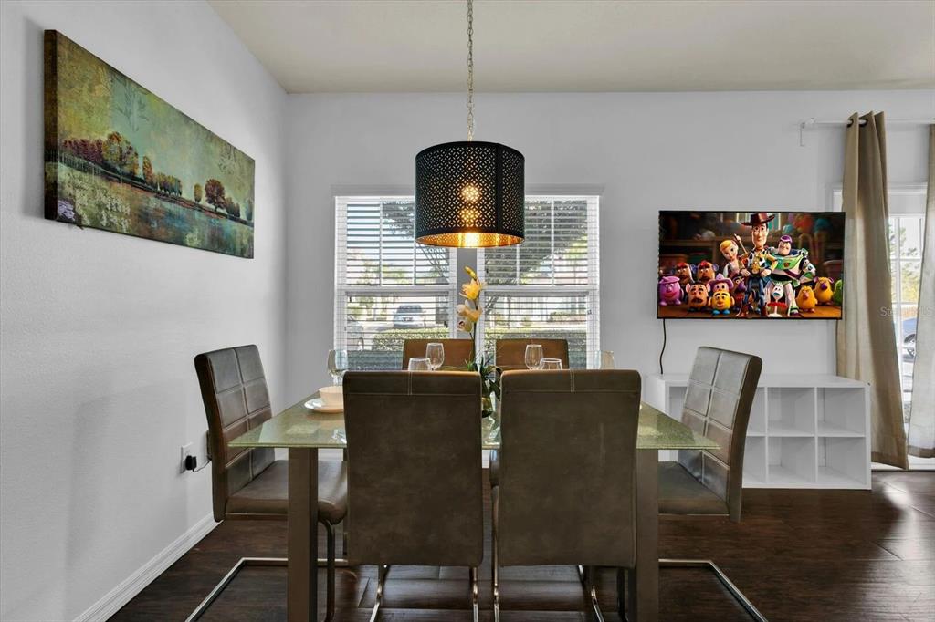 A dining room features a glass-topped table, four brown chairs, and a black pendant light — 3206 GOLD LANE, KISSIMMEE, FL