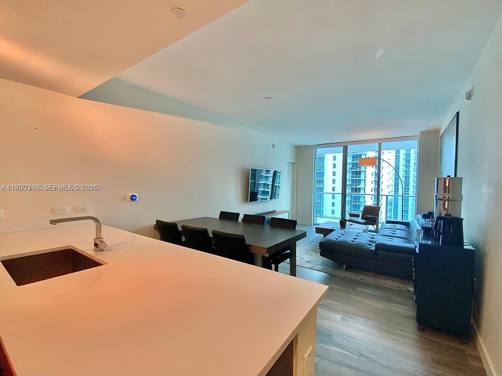 A modern open-concept living and dining area features a kitchen island and floor-to-ceiling windows — 1100 S Miami Ave # 2811, Miami FL 33130, MIAMI, FL