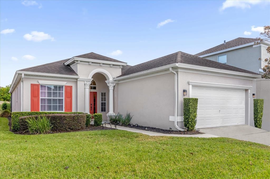 A single-story house with a beige stucco exterior, red shutters, and a two-car garage — 246 MONTARA DRIVE, DAVENPORT, FL