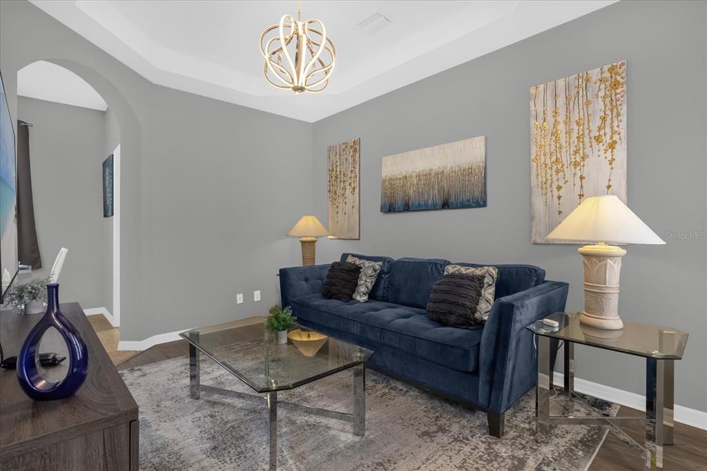 A living room features a blue velvet sofa, glass coffee table, and three wall art pieces — 246 MONTARA DRIVE, DAVENPORT, FL