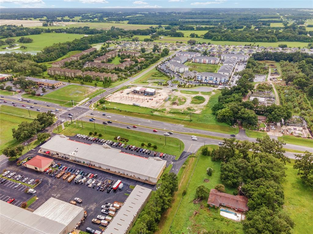 An aerial view shows a commercial plaza, a multi-lane road, and nearby residential apartment complexes — TBD N US HWY 301 Lot 3, WILDWOOD, FL