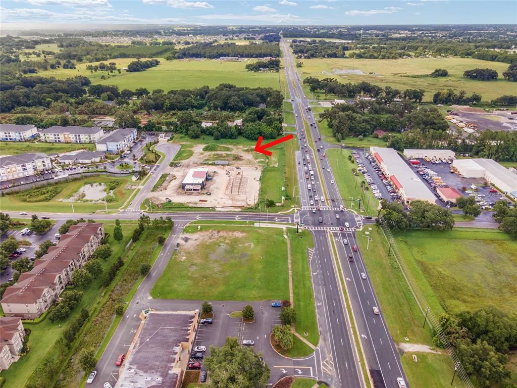An aerial view shows a construction site with a red arrow pointing toward the lot — TBD N US HWY 301 Lot 3, WILDWOOD, FL