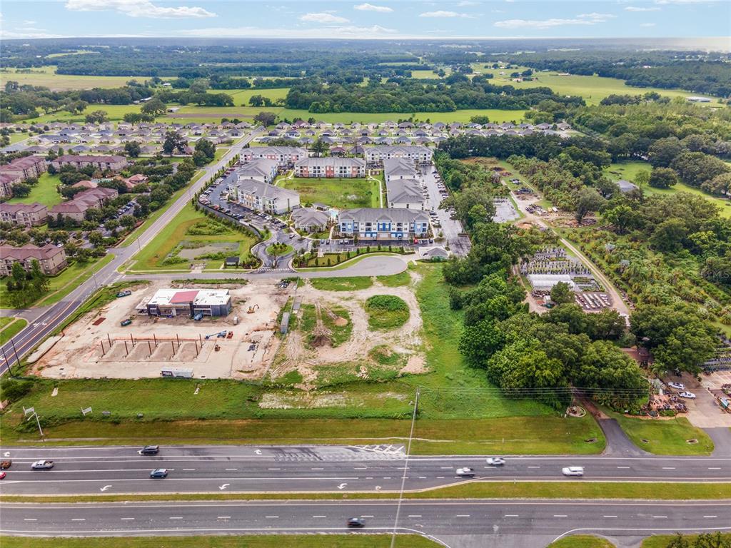 An aerial view shows a multi-story apartment complex adjacent to a construction site and highway — TBD N US HWY 301 Lot 3, WILDWOOD, FL