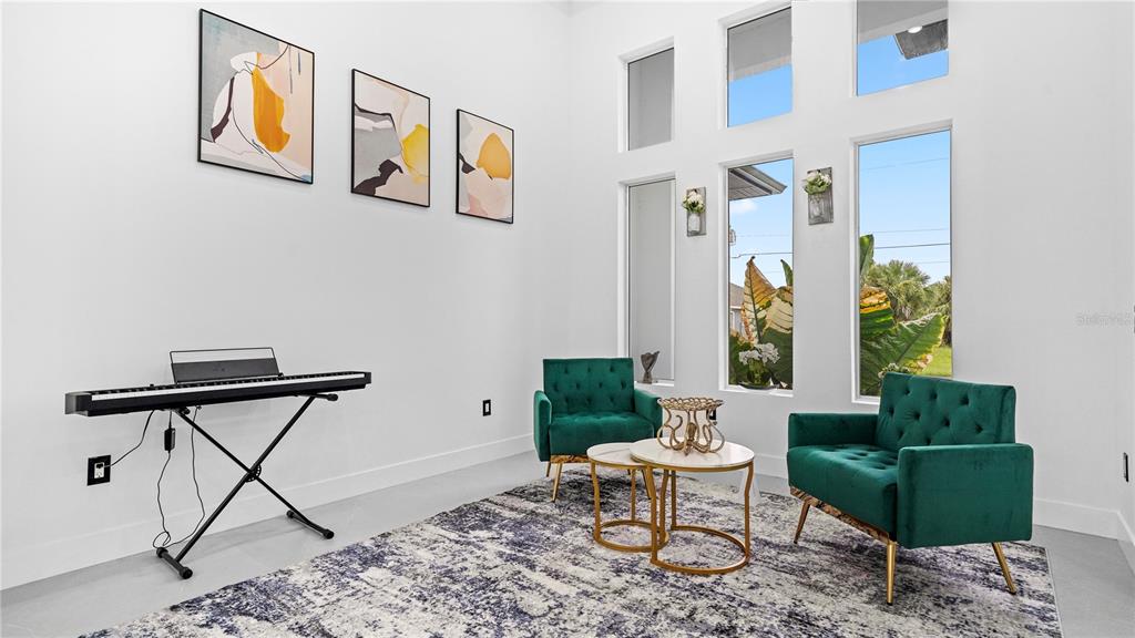 A bright room features a keyboard, two green velvet chairs, and a patterned area rug — 230 W PINE VALLEY LANE, ROTONDA WEST, FL