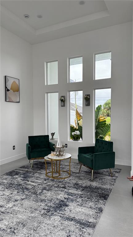 A living area features high ceilings, tall windows, two green velvet chairs, and a patterned rug — 230 W PINE VALLEY LANE, ROTONDA WEST, FL