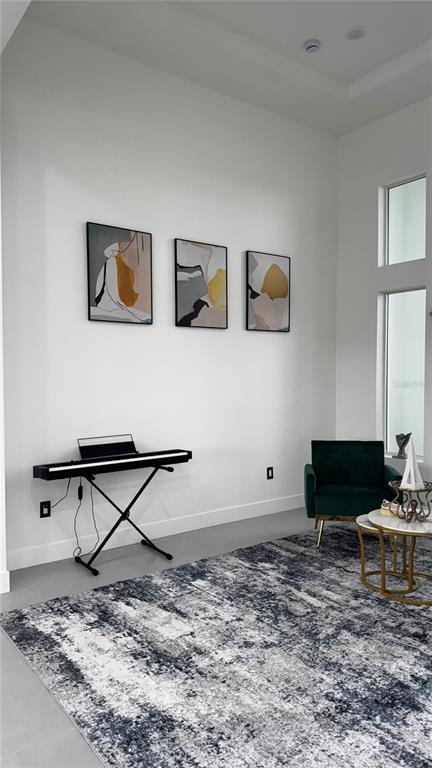 A modern room features a digital piano, a green armchair, and three abstract wall art pieces — 230 W PINE VALLEY LANE, ROTONDA WEST, FL