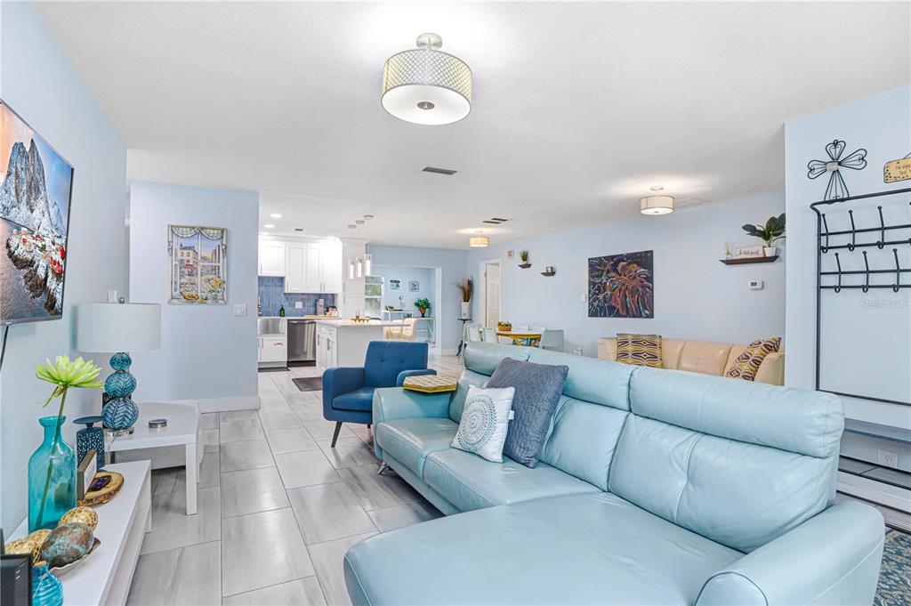A living room with light blue walls, tile flooring, and a large light blue sectional sofa — 12819 129TH TERRACE, LARGO, FL