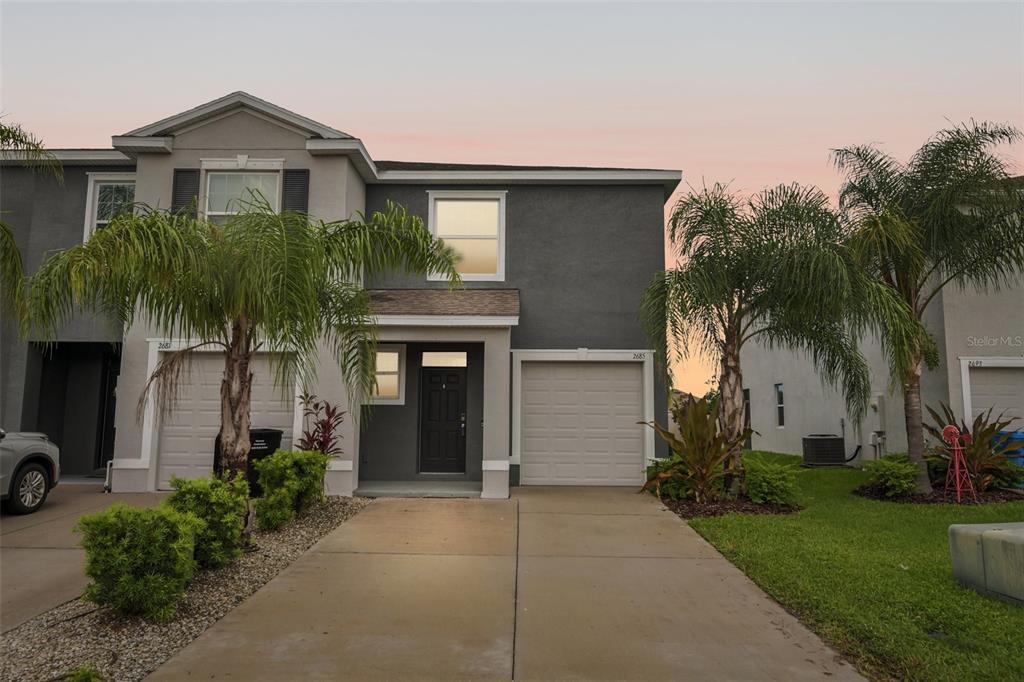 A two-story townhouse with a gray exterior, a single-car garage, and a concrete driveway — 2685 SUNCOAST BLEND DRIVE, ODESSA, FL