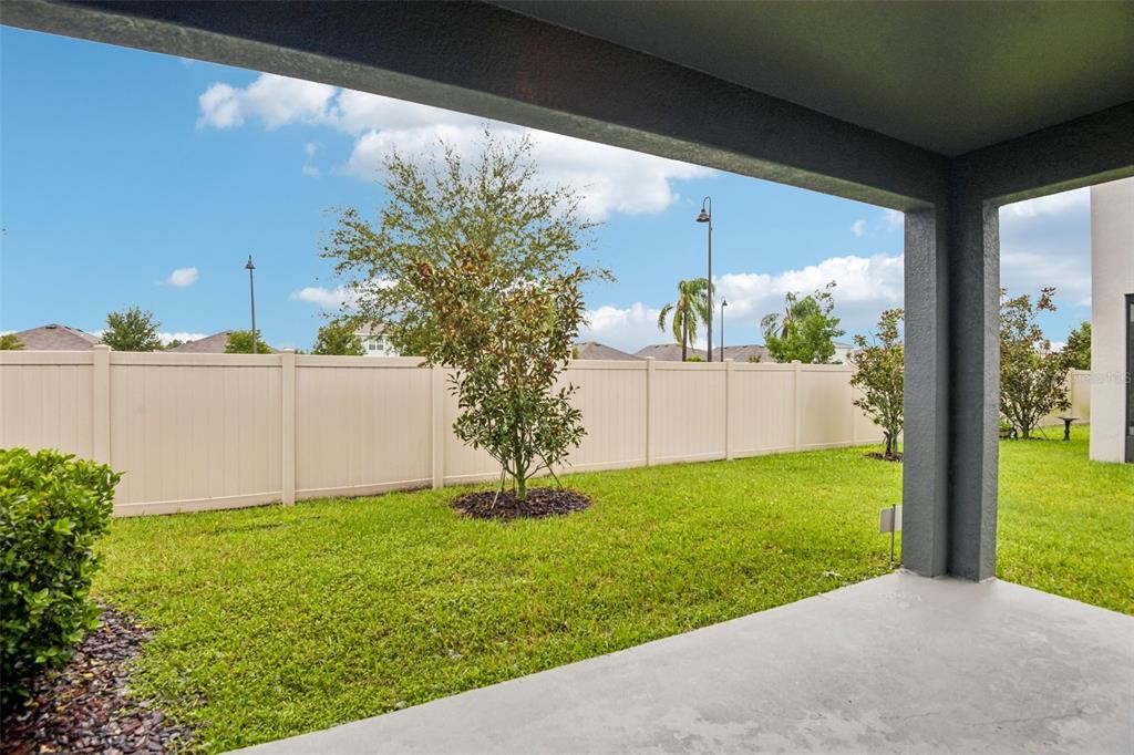 A view from a covered concrete patio looking out onto a grassy backyard with a fence — 2685 SUNCOAST BLEND DRIVE, ODESSA, FL
