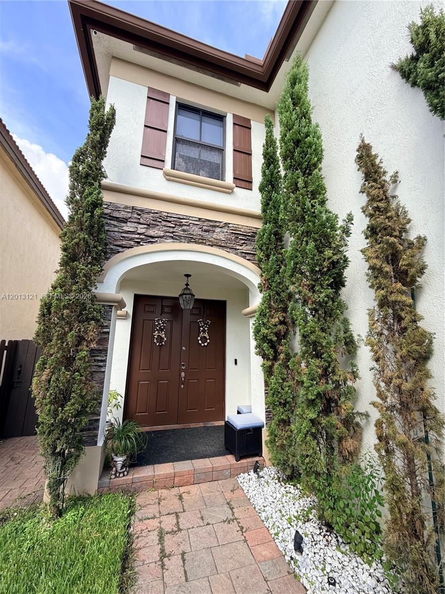 The exterior of a two-story home features a stone-accented entryway with double brown doors — 8640 NW 101st Pl, Doral FL 33178, DORAL, FL