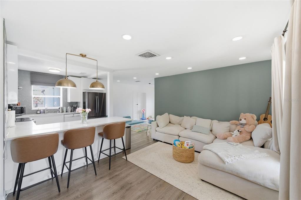 A kitchen with a breakfast bar overlooks a living area featuring a sage green wall — 2150 76TH STREET N, ST PETERSBURG, FL