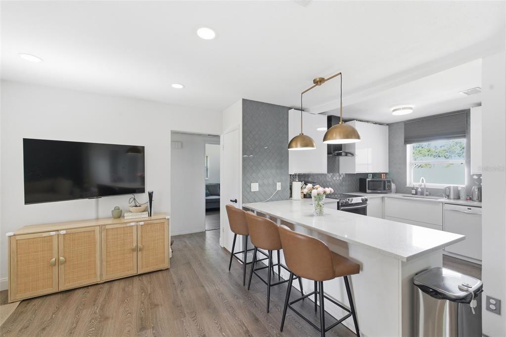 A kitchen with white cabinets, a gray tiled backsplash, and a breakfast bar with stools — 2150 76TH STREET N, ST PETERSBURG, FL