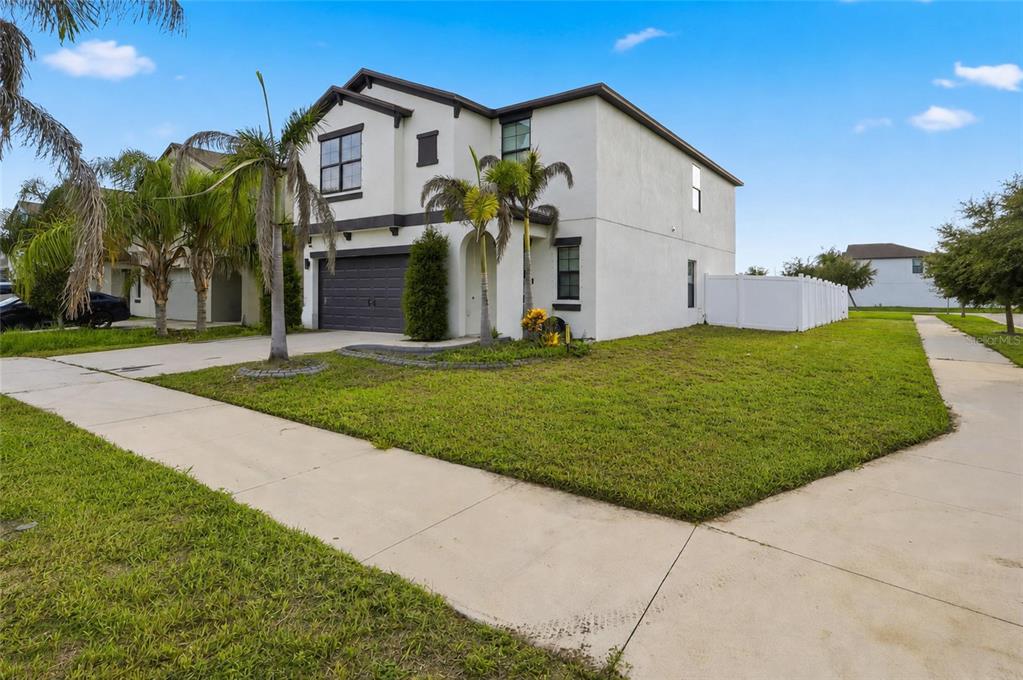 A two-story stucco house with a two-car garage and palm trees in the front yard — 14801 BOULDER PASS PLACE, WIMAUMA, FL