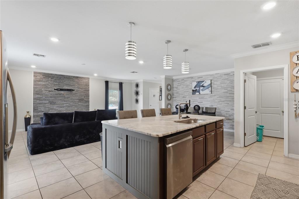 A kitchen island with a stone countertop sits in front of a living area with stone walls — 14801 BOULDER PASS PLACE, WIMAUMA, FL
