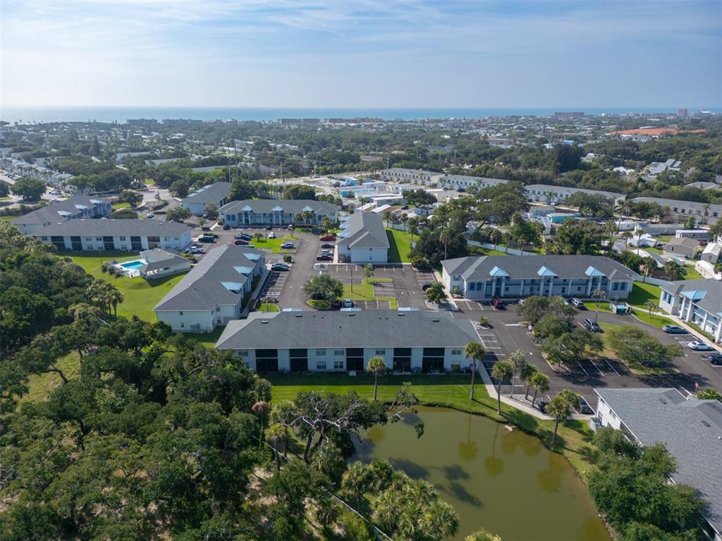 An aerial view of a multi-building apartment complex with a pond and parking lots — 150 PORTSIDE AVENUE UNIT 103, CAPE CANAVERAL, FL