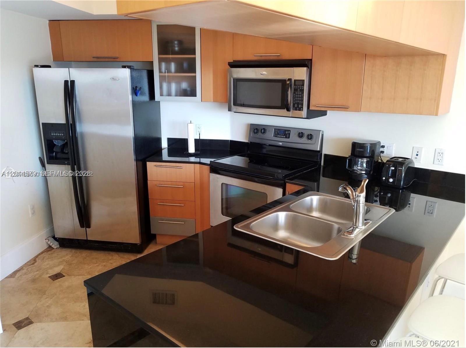 A kitchen features light wood cabinets, black countertops, stainless steel appliances, and a double sink — 1750 N Bayshore Dr # 3114, Miami FL 33132, MIAMI, FL