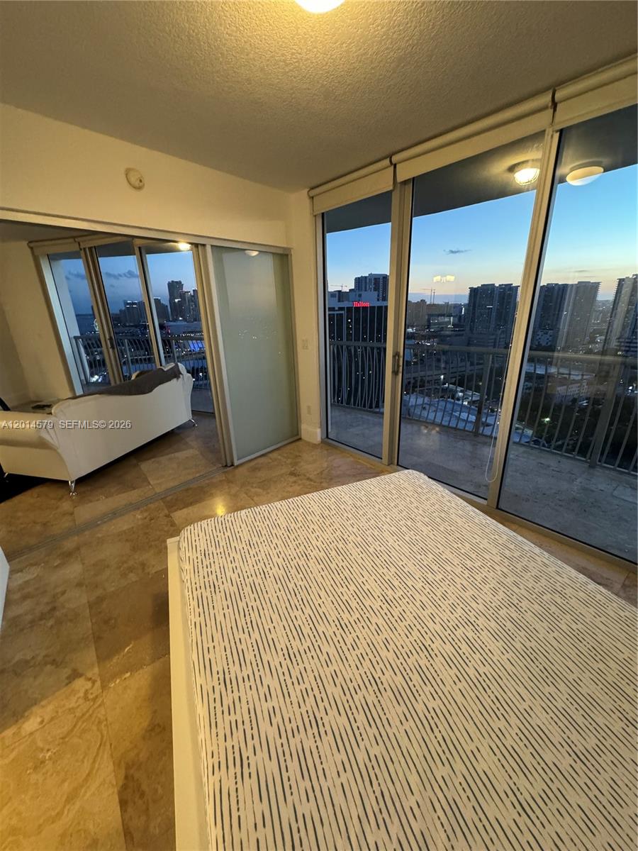 A bedroom with marble floors features a bed and sliding glass doors opening to balconies — 1750 N Bayshore Dr # 3114, Miami FL 33132, MIAMI, FL