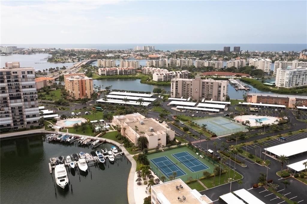 An aerial view shows a waterfront condominium complex with boat slips, tennis courts, and parking — 7405 BAY ISLAND DRIVE S UNIT 224, SOUTH PASADENA, FL