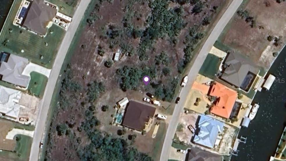 This aerial view shows a residential property with a house, driveway, and surrounding wooded land — 8245 ARLEWOOD CIRCLE, PORT CHARLOTTE, FL