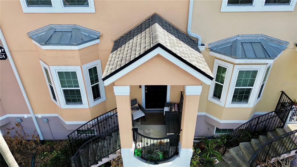 An elevated view of a home entrance with a covered porch and symmetrical bay windows — 6624 TIME SQUARE AVENUE UNIT 102, ORLANDO, FL