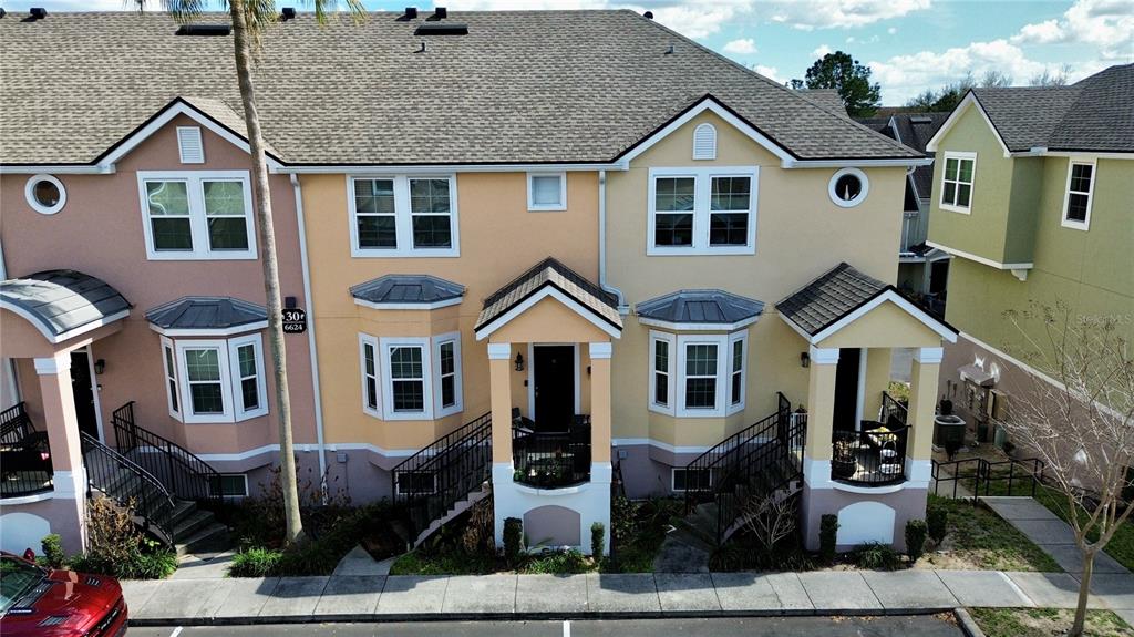 An exterior view of a multi-story townhouse complex with beige and pink siding — 6624 TIME SQUARE AVENUE UNIT 102, ORLANDO, FL