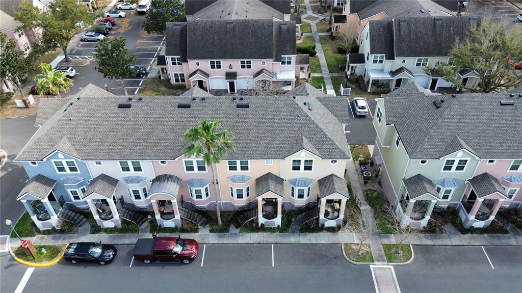 An aerial view shows a row of colorful townhouses with gray roofs and parking spaces — 6624 TIME SQUARE AVENUE UNIT 102, ORLANDO, FL