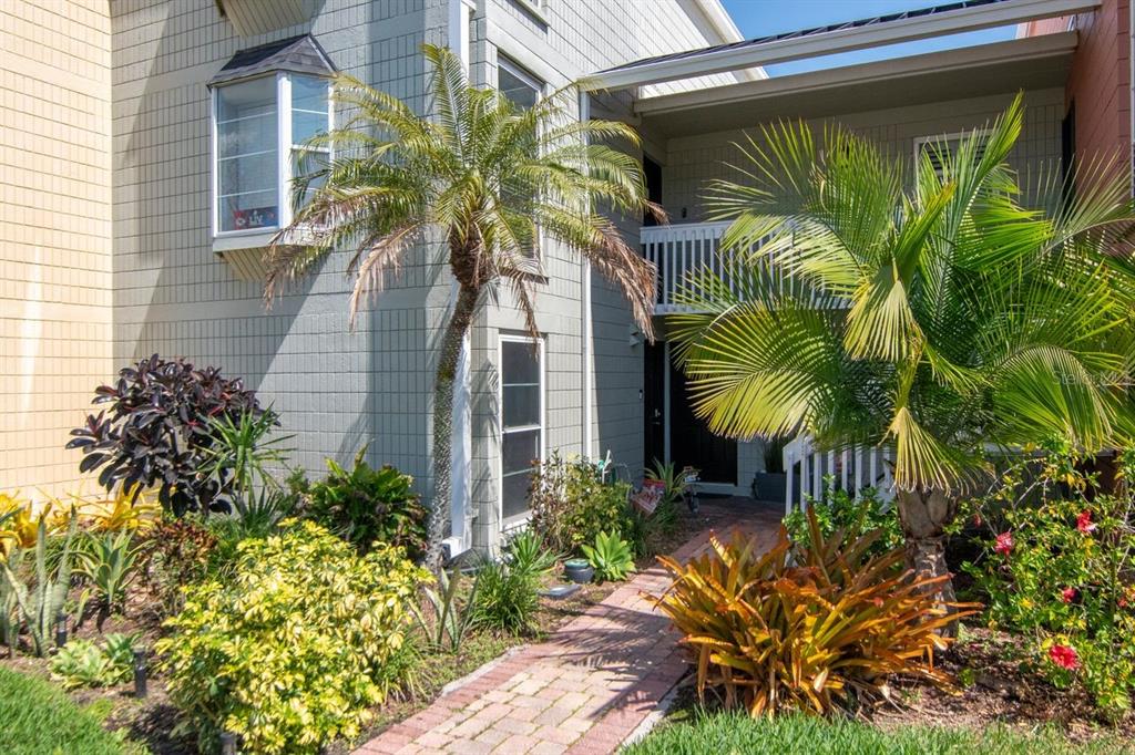A brick walkway leads to the entrance of a gray multi-story building with palm trees — 2424 W TAMPA BAY BOULEVARD UNIT C105, TAMPA, FL