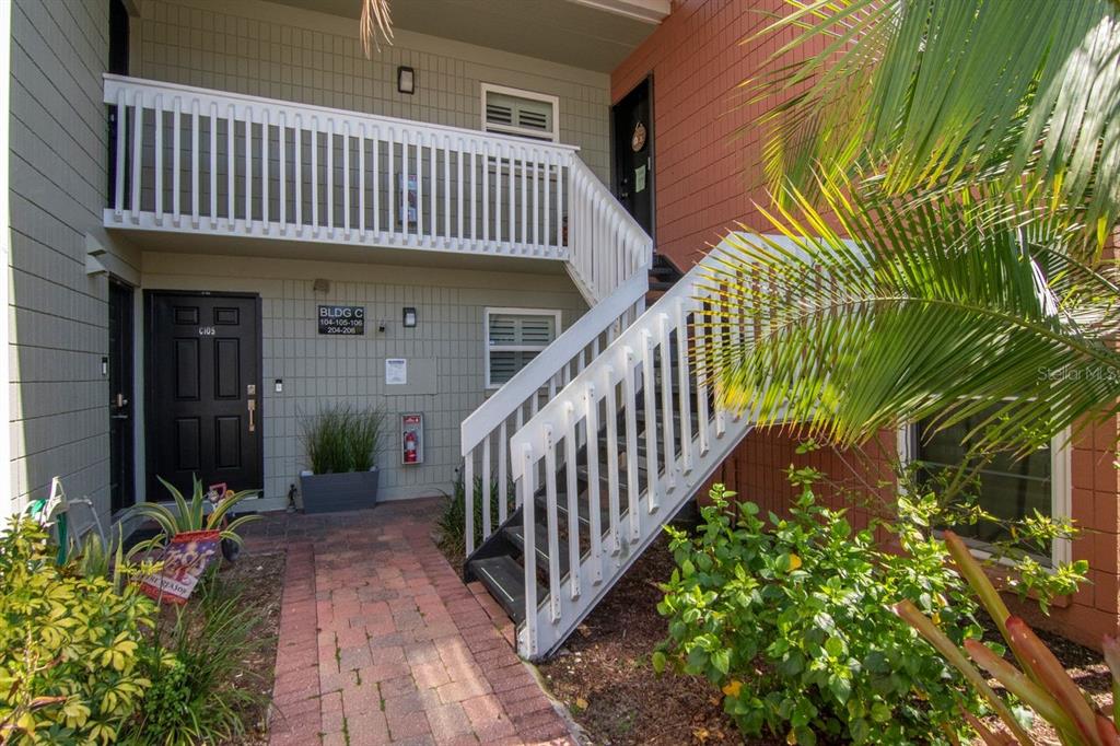 An exterior view of a two-story apartment building with a brick walkway and staircase — 2424 W TAMPA BAY BOULEVARD UNIT C105, TAMPA, FL