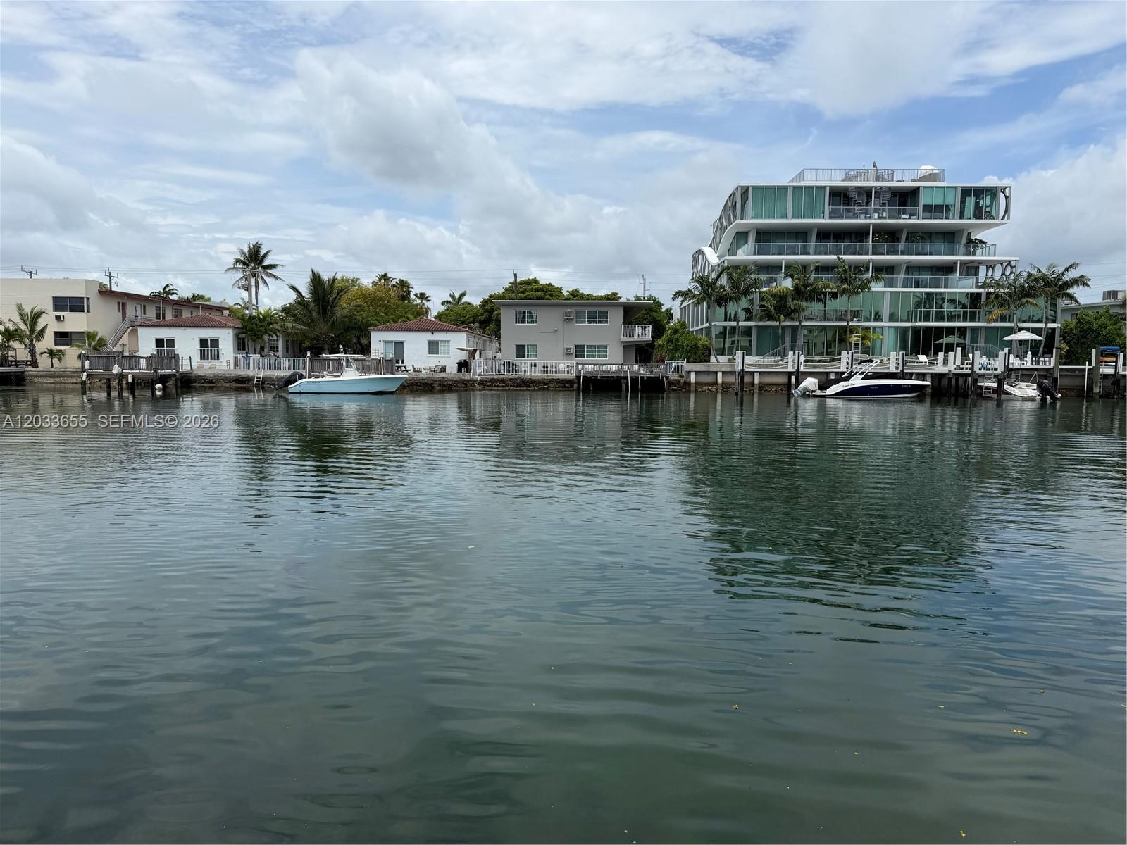 A view of a canal with several houses and a modern apartment building along the shore — 8420 Byron Ave # 6, Miami Beach FL 33141, MIAMI BEACH, FL
