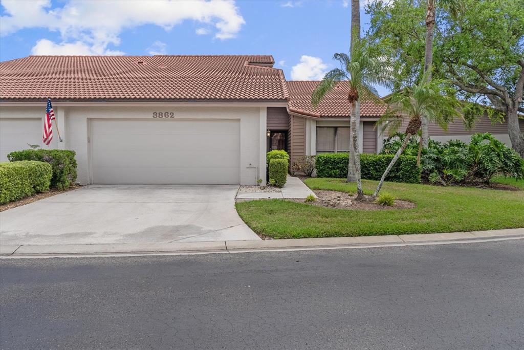 A single-story house with a tile roof, a two-car garage, and a small front yard — 3862 WILSHIRE CIRCLE W UNIT 107, SARASOTA, FL
