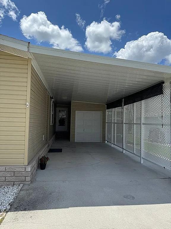 A concrete carport with a white lattice privacy screen sits beside a tan home — 57 STRAPHMORE DRIVE, HAINES CITY, FL