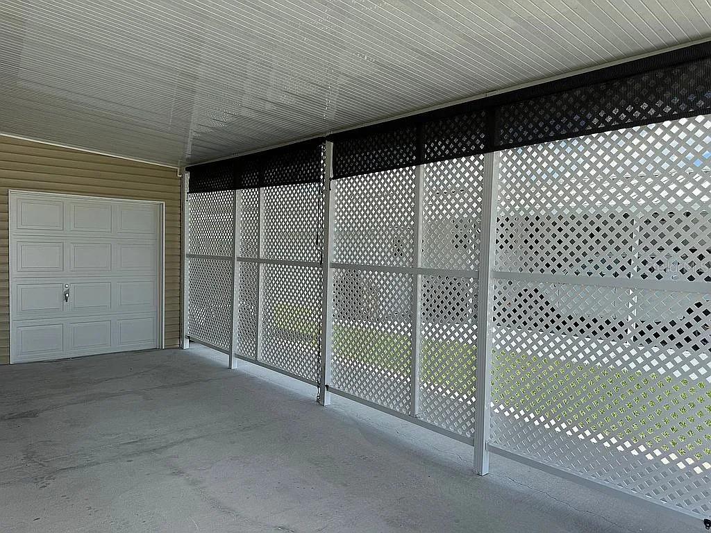 A covered carport features white lattice privacy screens and a white garage door — 57 STRAPHMORE DRIVE, HAINES CITY, FL