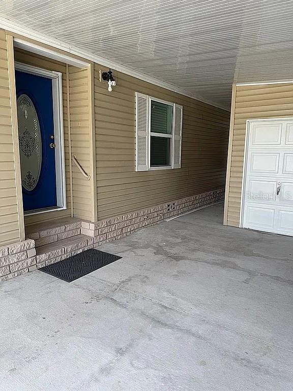 A blue front door and a white garage door are visible on this tan-sided home — 57 STRAPHMORE DRIVE, HAINES CITY, FL