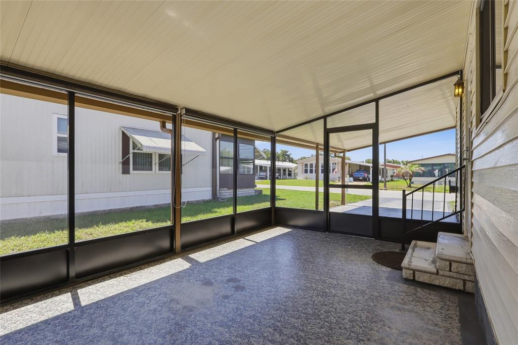 A covered, screened-in porch with a concrete floor and steps leading to the house — 35919 VERANO LANE, ZEPHYRHILLS, FL