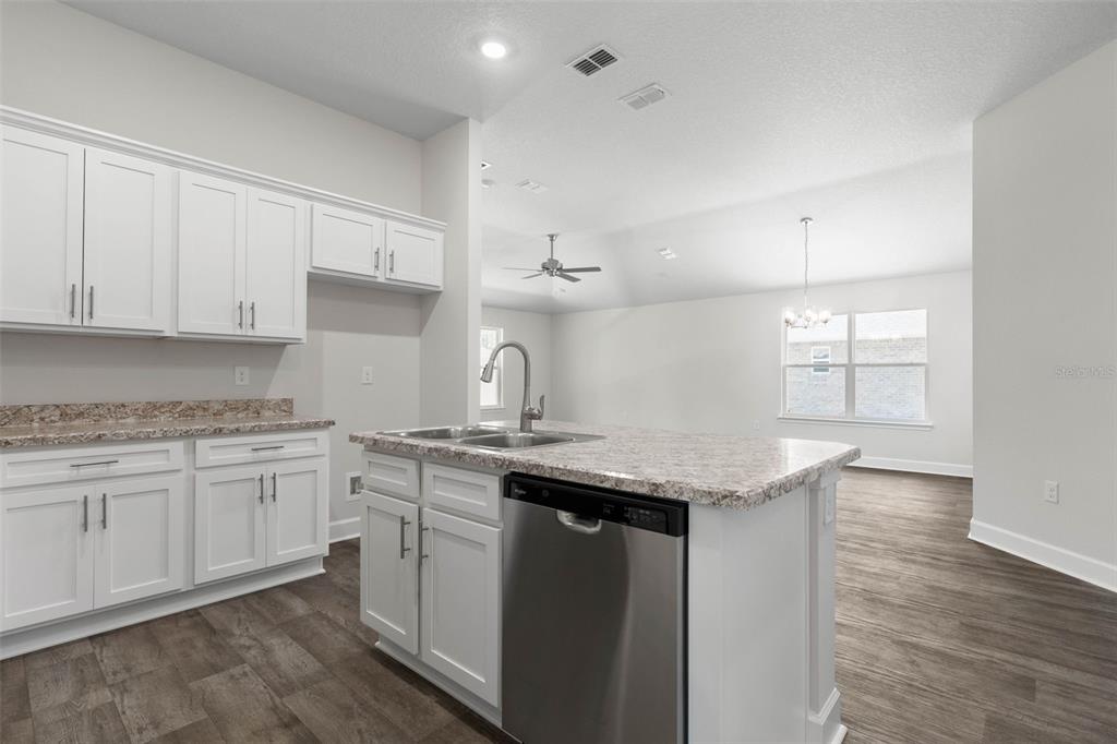 A kitchen with white cabinets, granite countertops, a center island, and wood-look flooring — 23 PRETORIA LANE, PALM COAST, FL