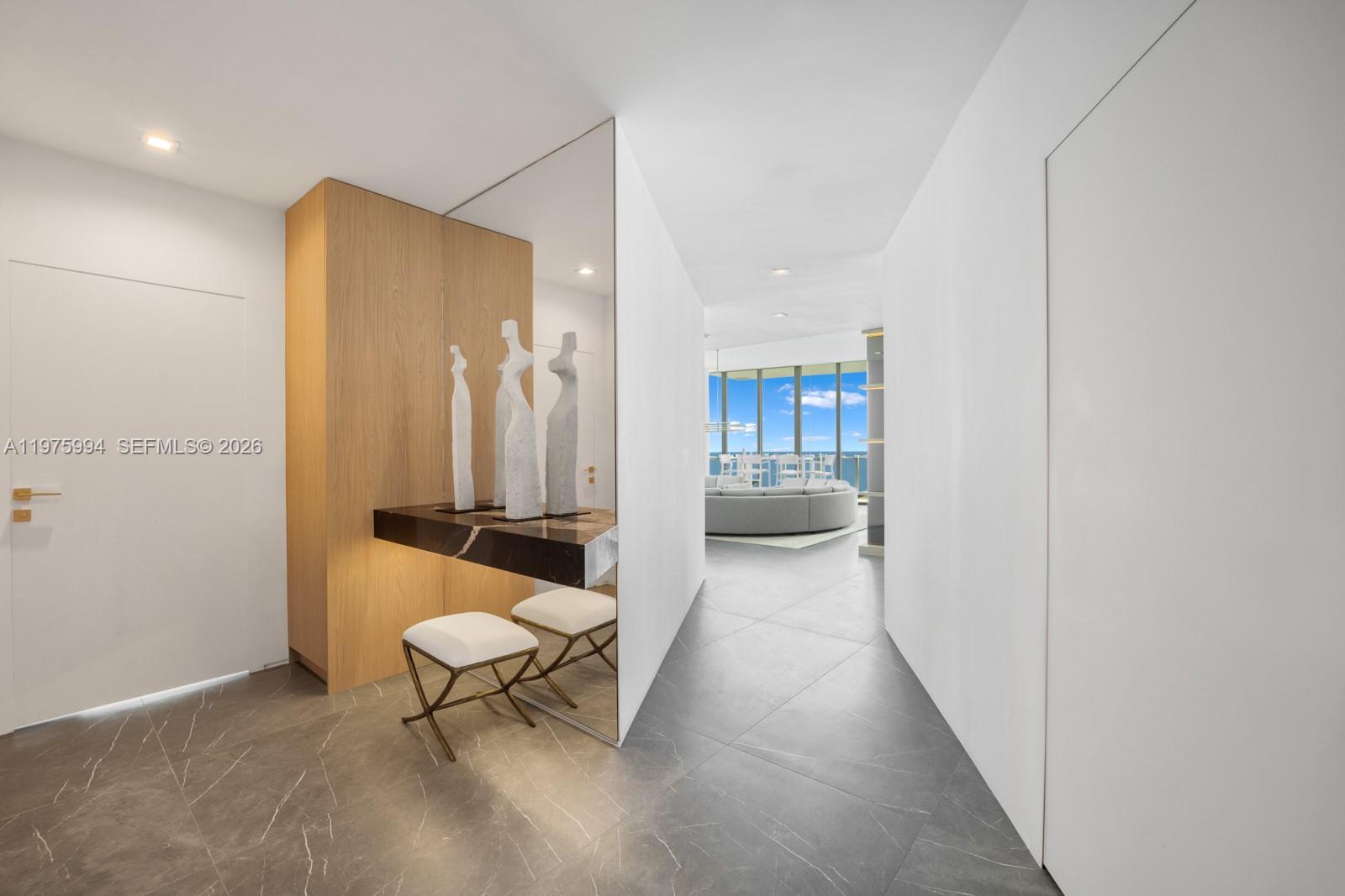 A modern entryway features a marble console table, sculptural decor, and a view into a living area — 2900 NE 7th Ave # 4602, Miami FL 33137, MIAMI, FL